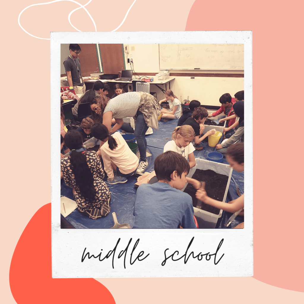 image of children bending over large crates of dirt with digging tools